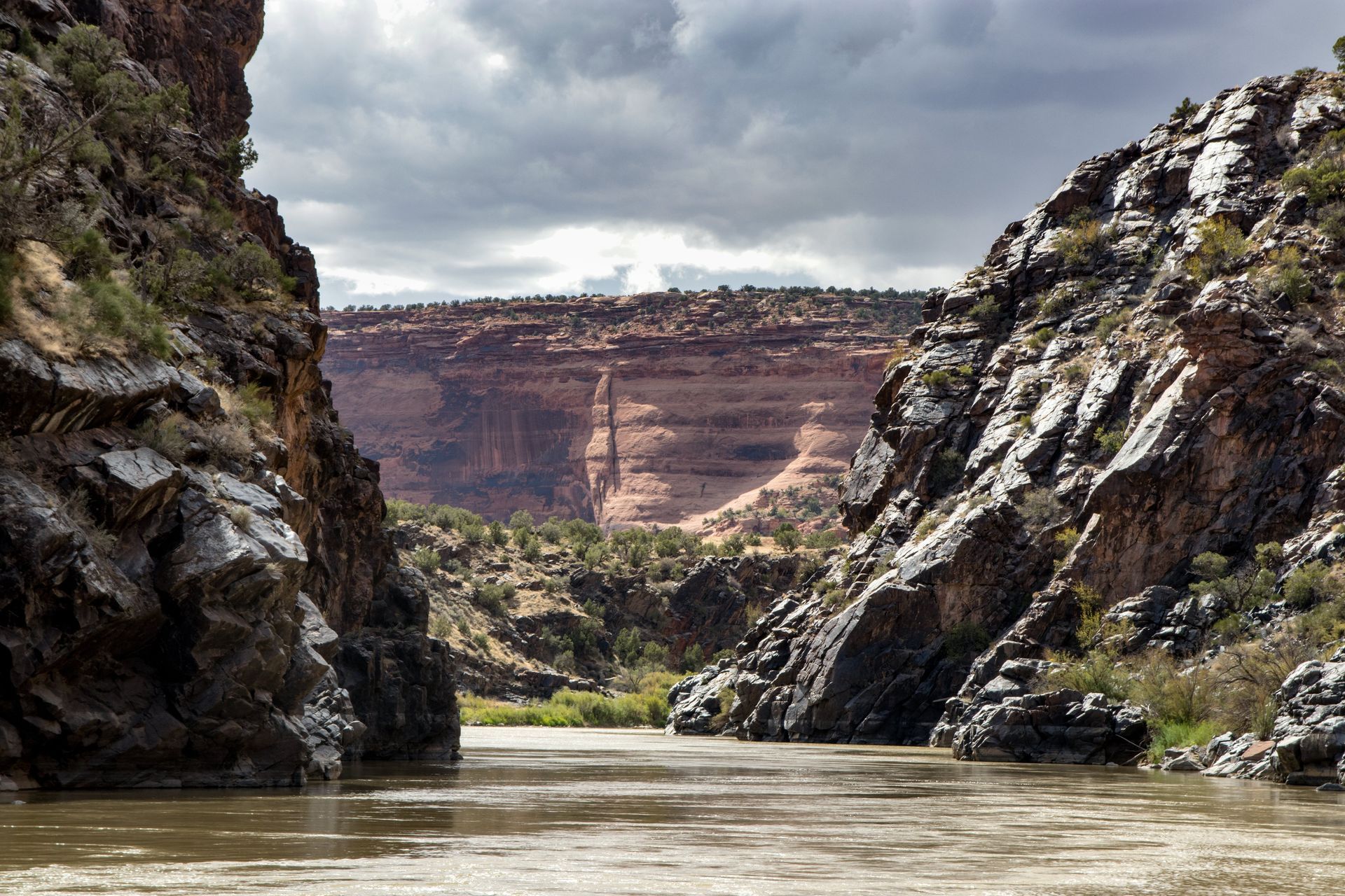 River flowing between rocky canyon walls under a cloudy sky.