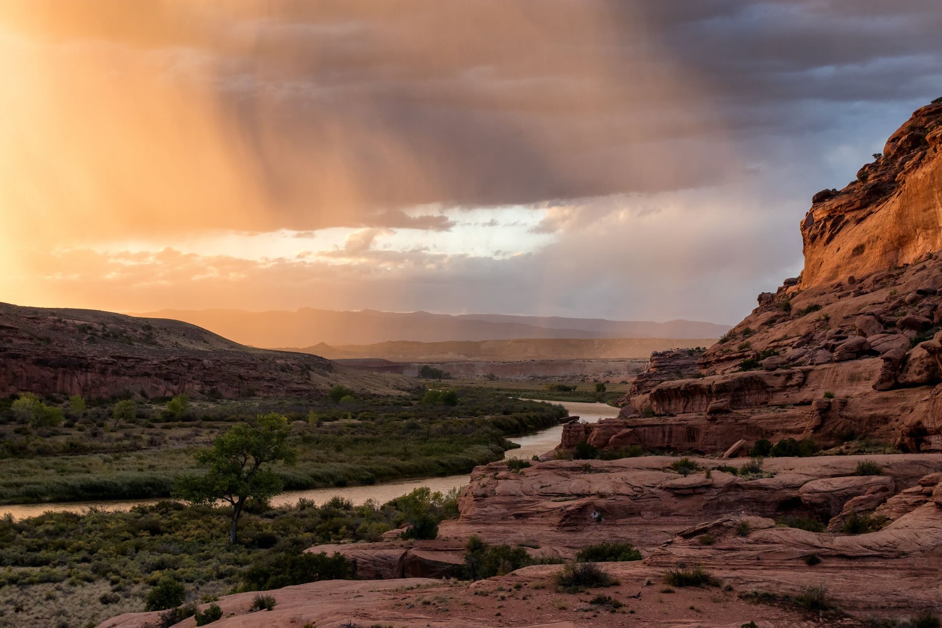 Red rock canyon landscape with a river and sunset with rain.