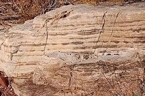 Layered sandstone rock formation, with light brown and darker brown horizontal bands.