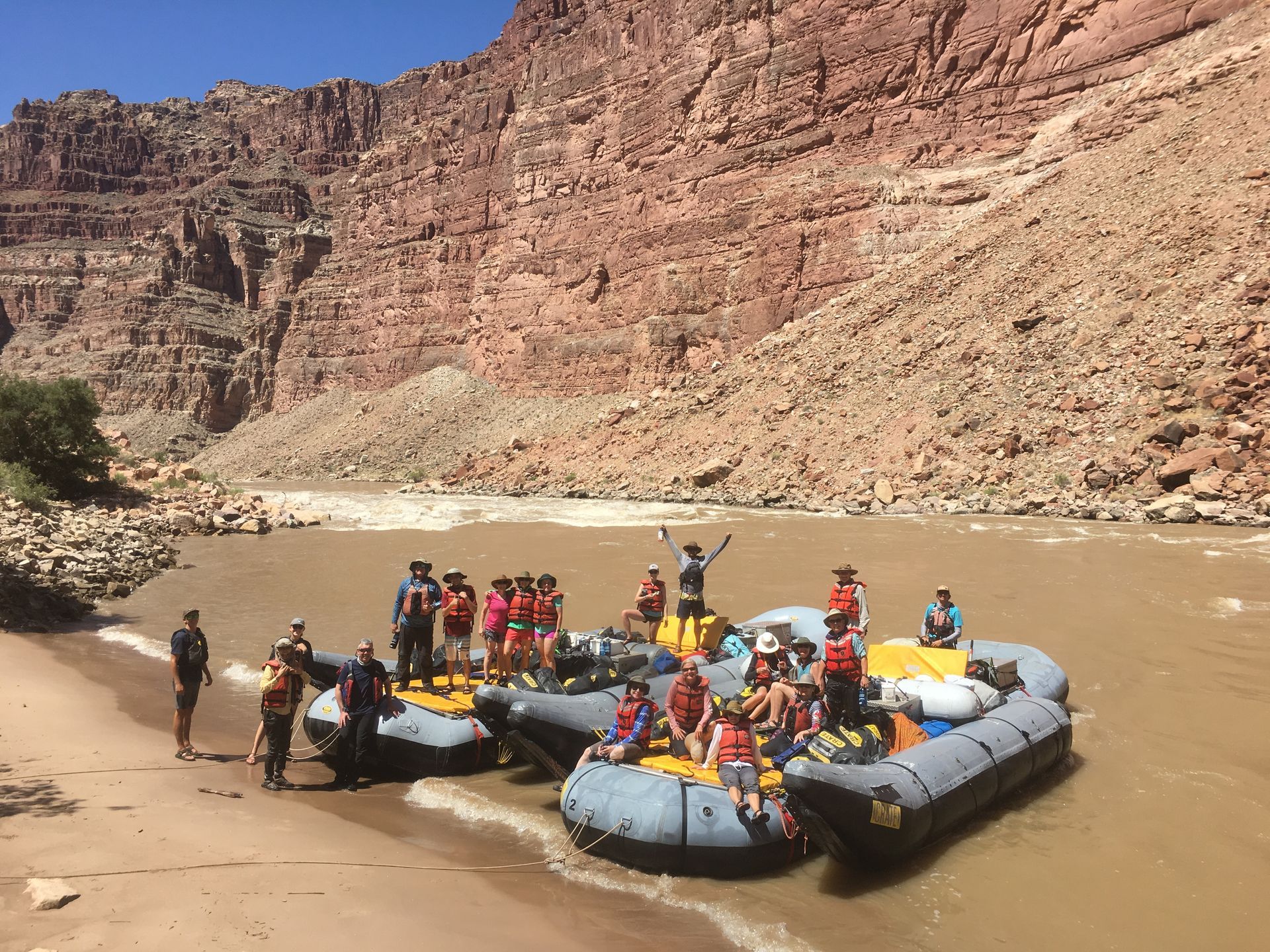 People on rafts by a river, near a canyon.