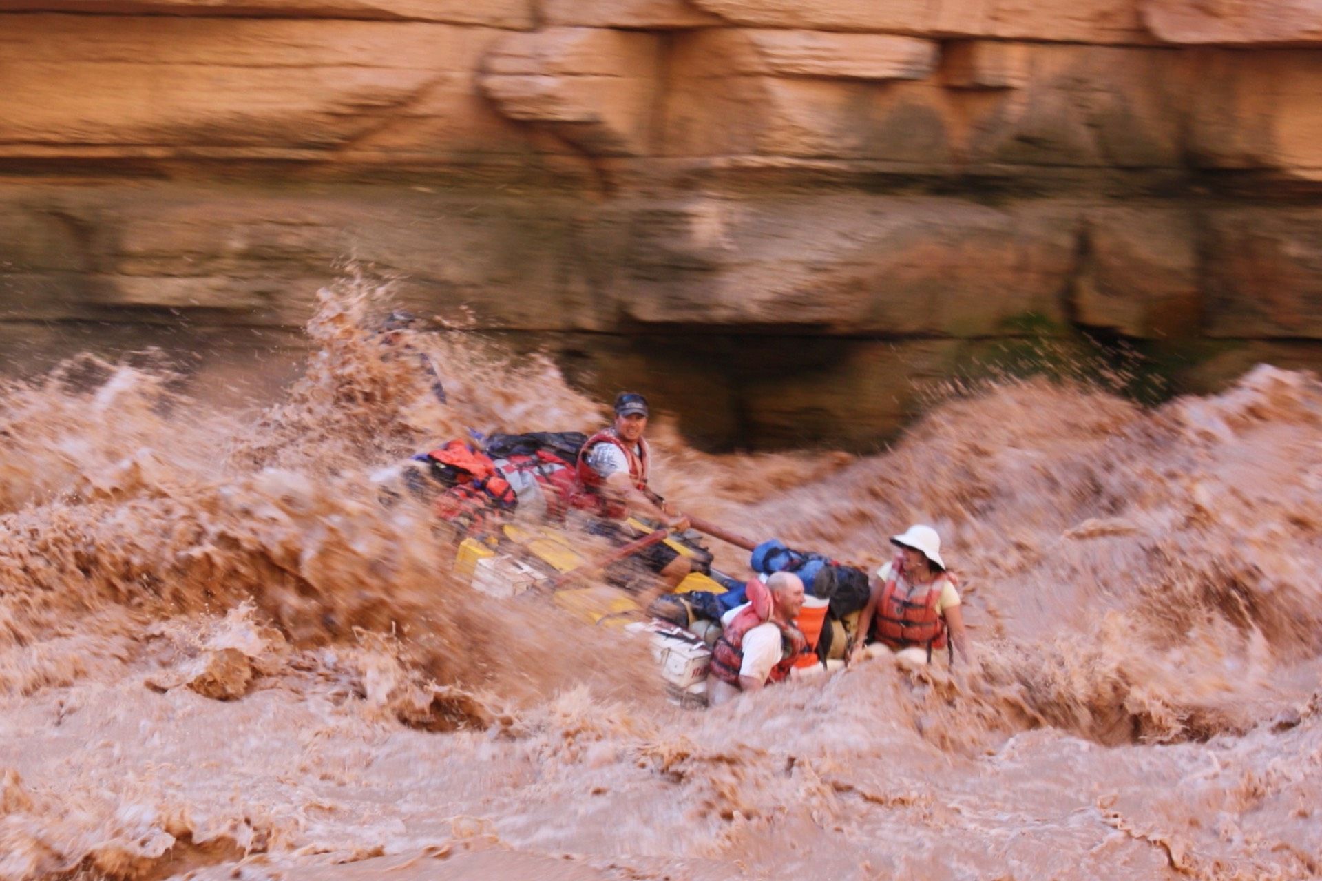Rafting through churning, muddy water in a canyon.