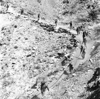 Men working on a steep, rocky mountain path, possibly building or repairing it.