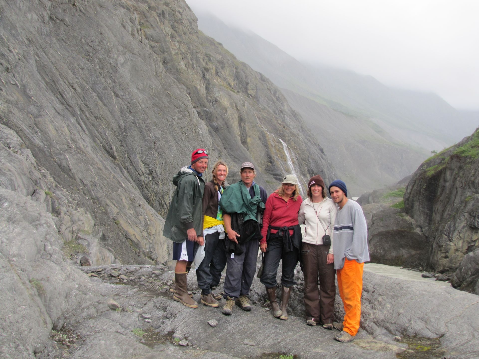 Group of hikers posing near a rocky canyon on a misty day.