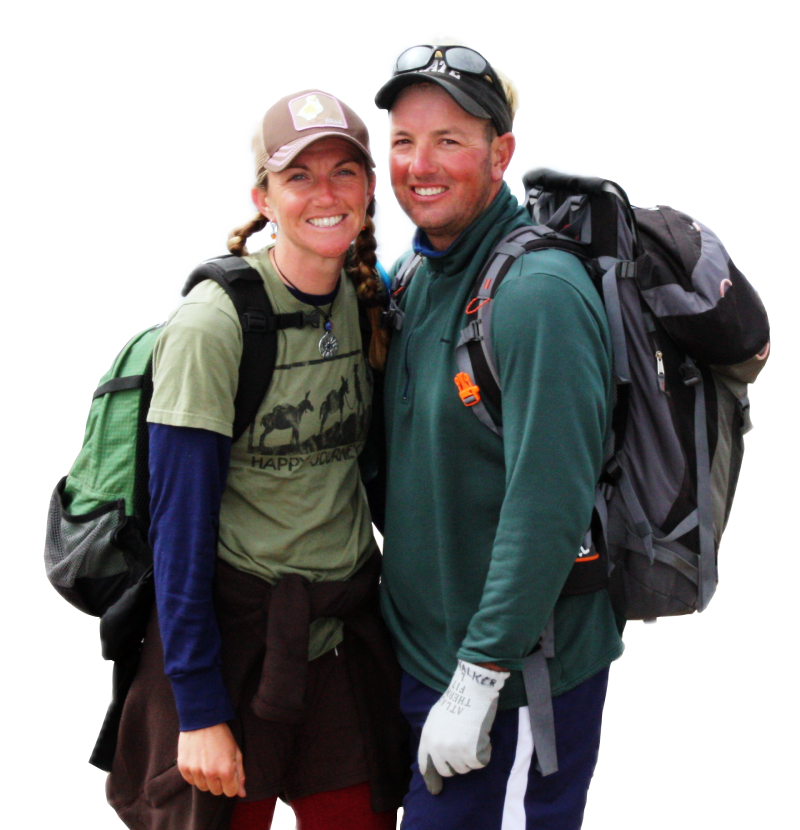Couple smiling with backpacks, likely hiking or backpacking. One wears a green shirt, the other a green long sleeve.
