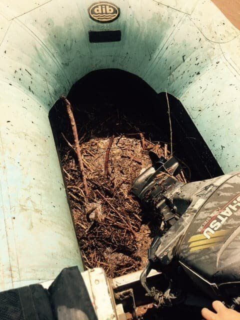 Interior of a light blue inflatable boat filled with debris and an outboard motor.