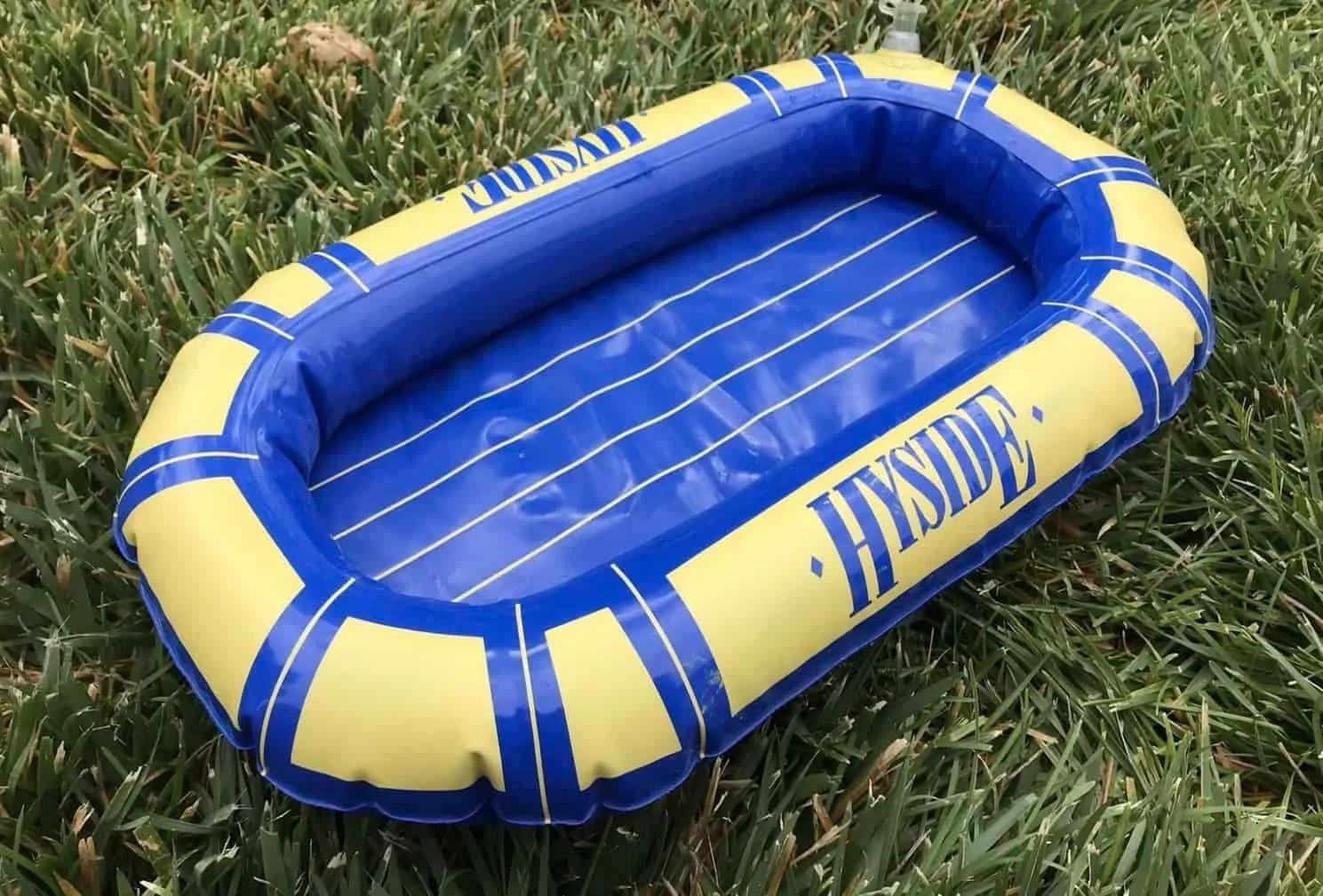 Blue and yellow inflatable raft on green grass, HY SIDE logo visible.