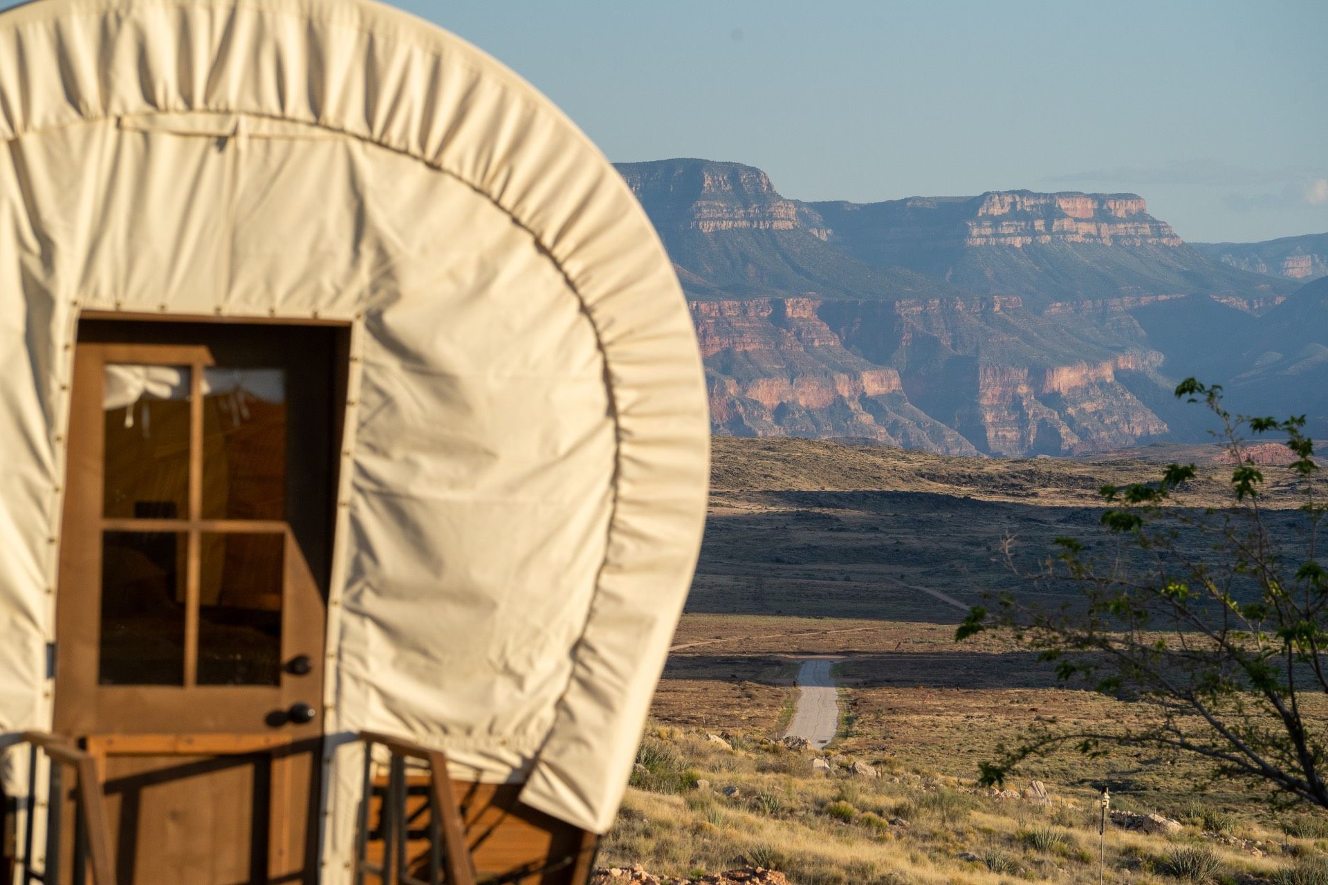Covered wagon with wooden door overlooking a desert landscape and mesas.
