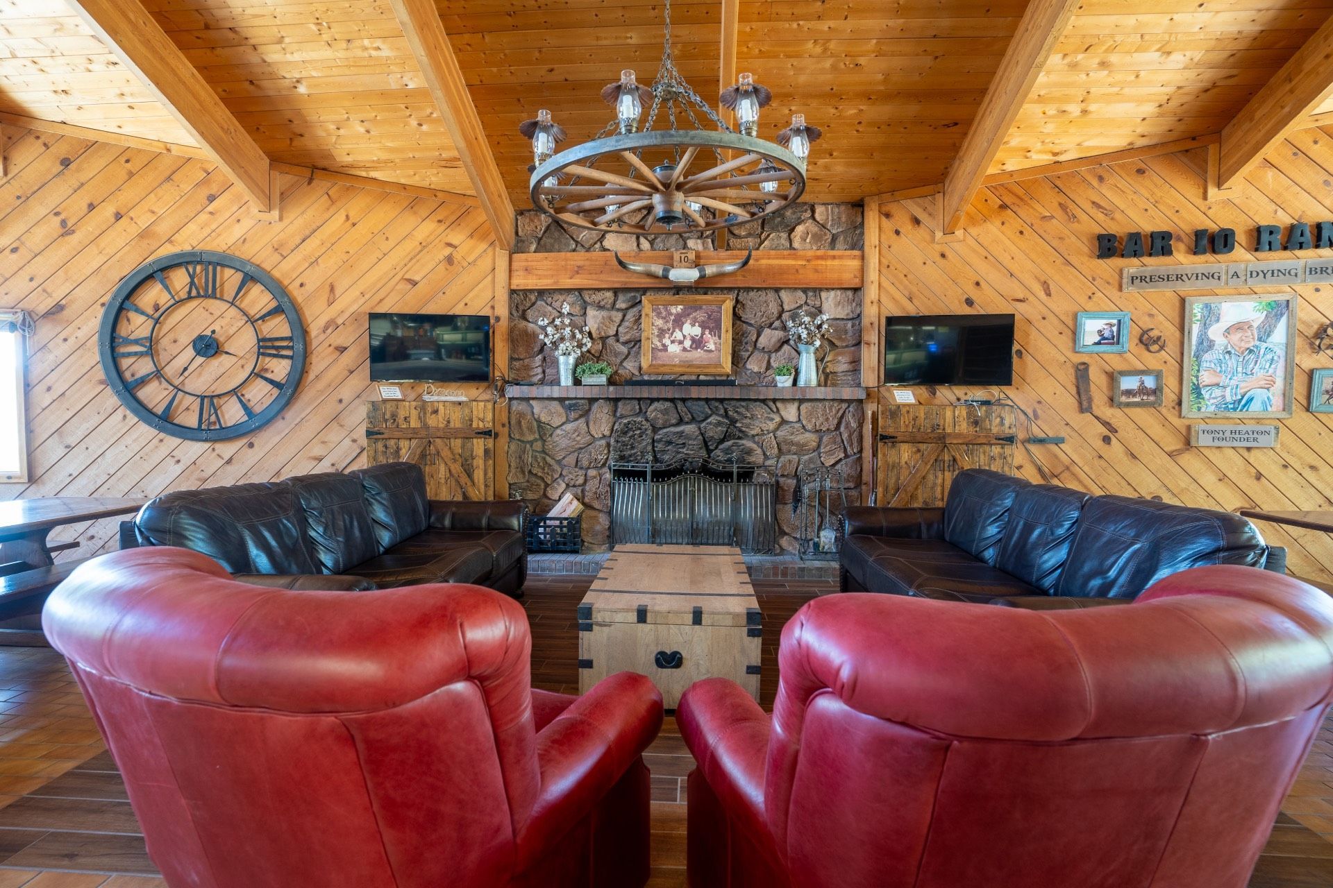 Lounge with a fireplace, leather furniture, wooden walls, and a large clock.