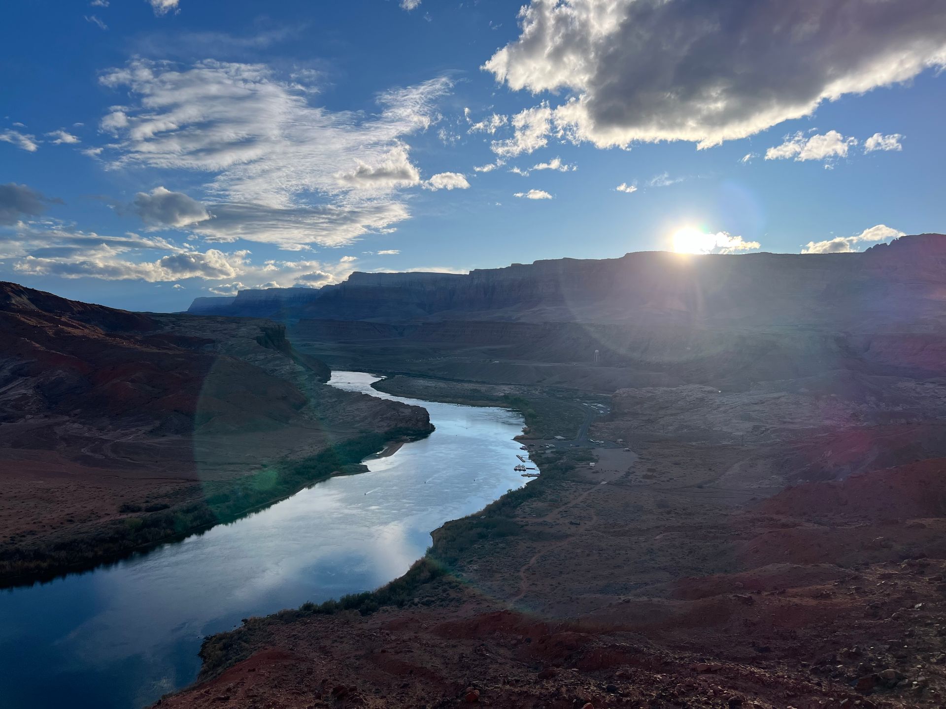 River winds through a canyon at sunset, with sun reflecting on the water.