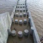 Concrete pier supports in water, with surrounding concrete walls.