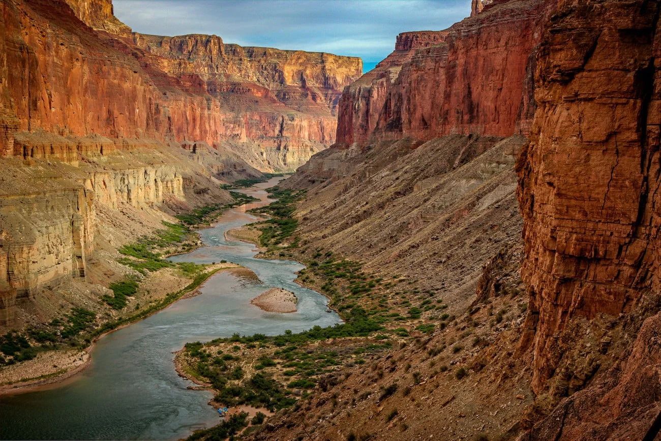 Canyon with river winding through, red rock walls, blue sky.