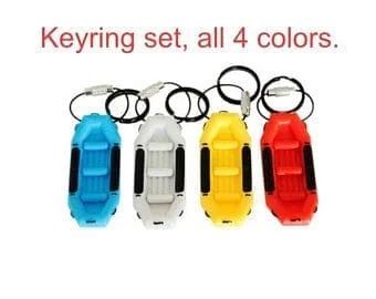 Keyring set: Four colorful toy boat keychains in blue, white, yellow, and red.