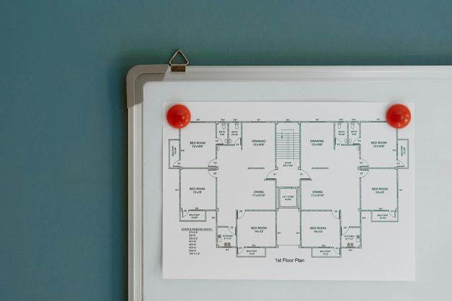 Una persona sta disegnando una casa su una planimetria con una penna.