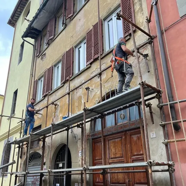 Un uomo è in piedi su un'impalcatura sul lato di un edificio.