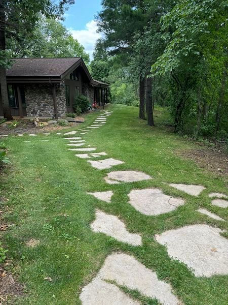 A stone path leading to a stone house in the woods.