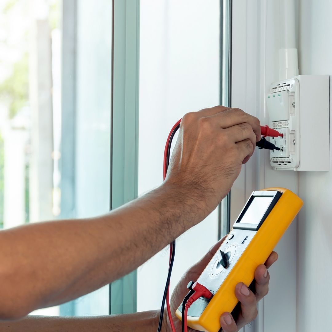 A man is using a multimeter to test an electrical outlet