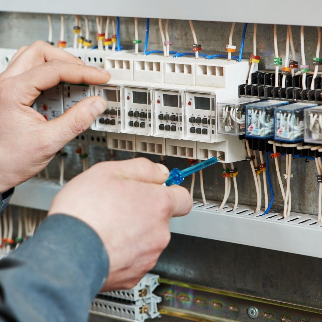 A person is working on an electrical panel with a screwdriver.