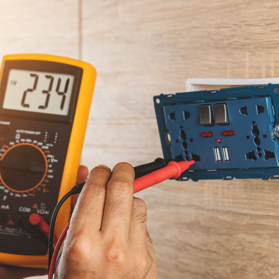 A person is using a multimeter to test an electrical outlet
