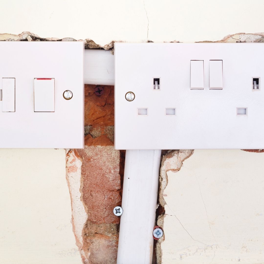 A close up of a white electrical outlet on a brick wall