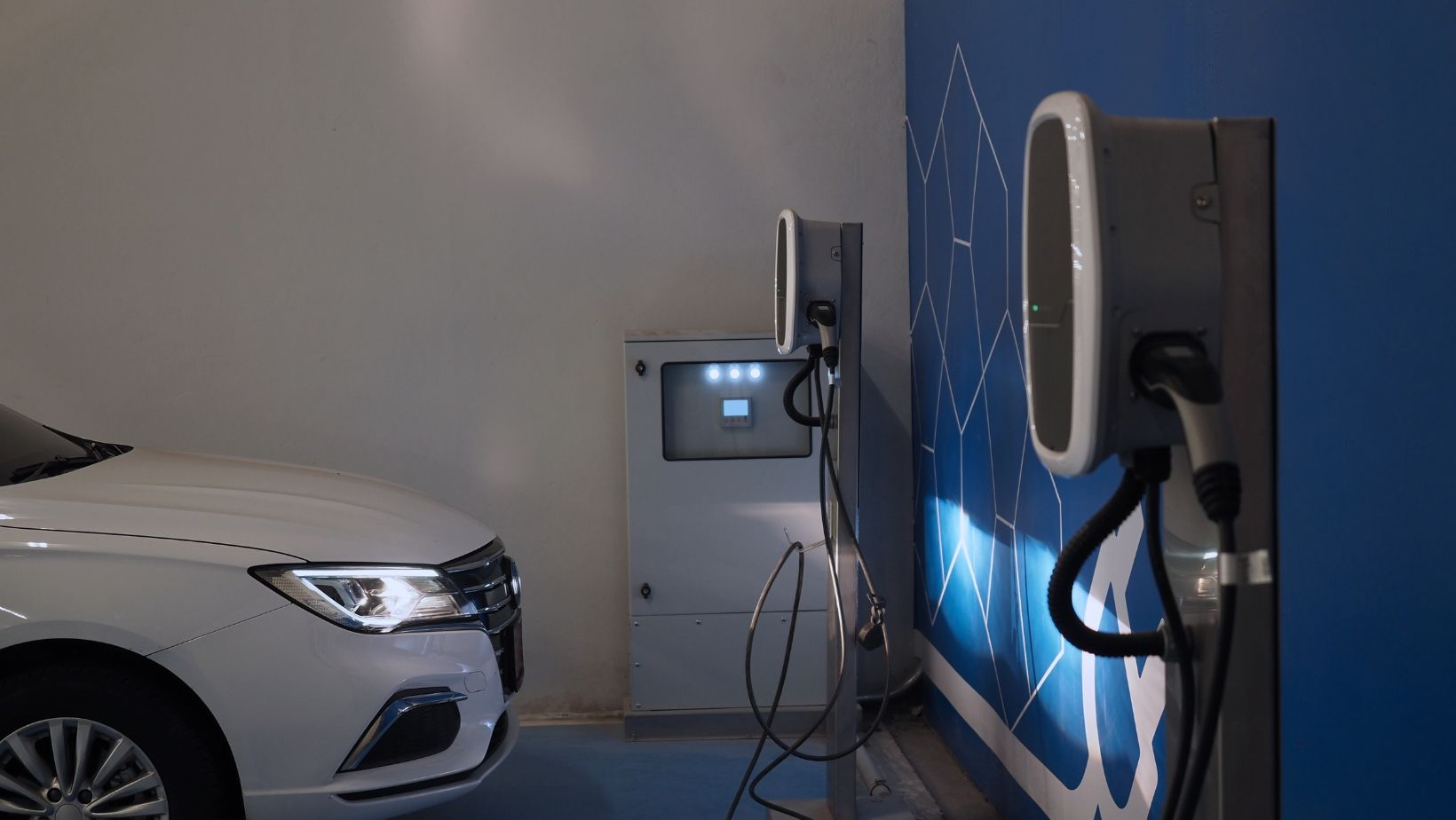 A white electric car is being charged at a charging station.