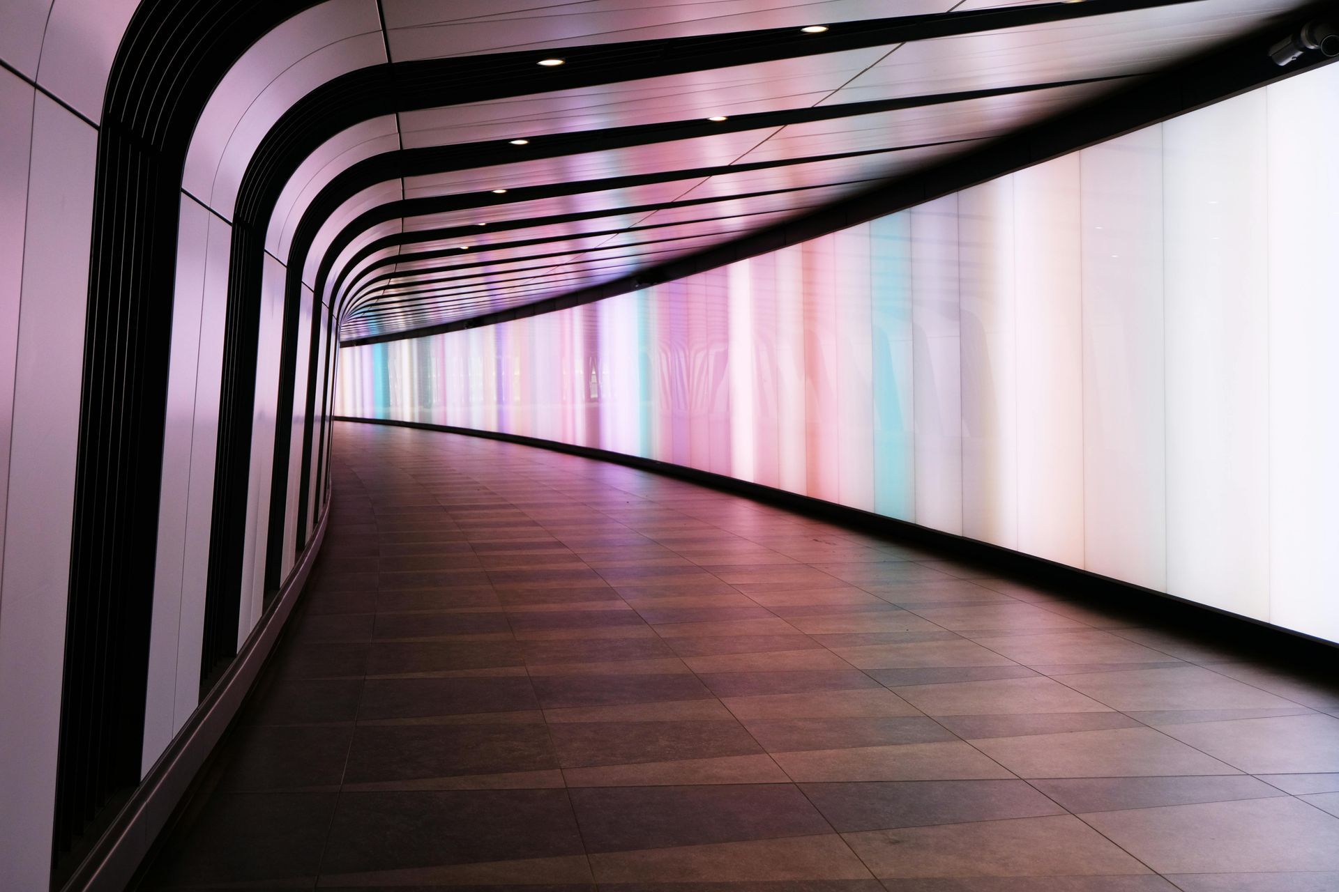 An empty tunnel with a rainbow of lights on the wall.