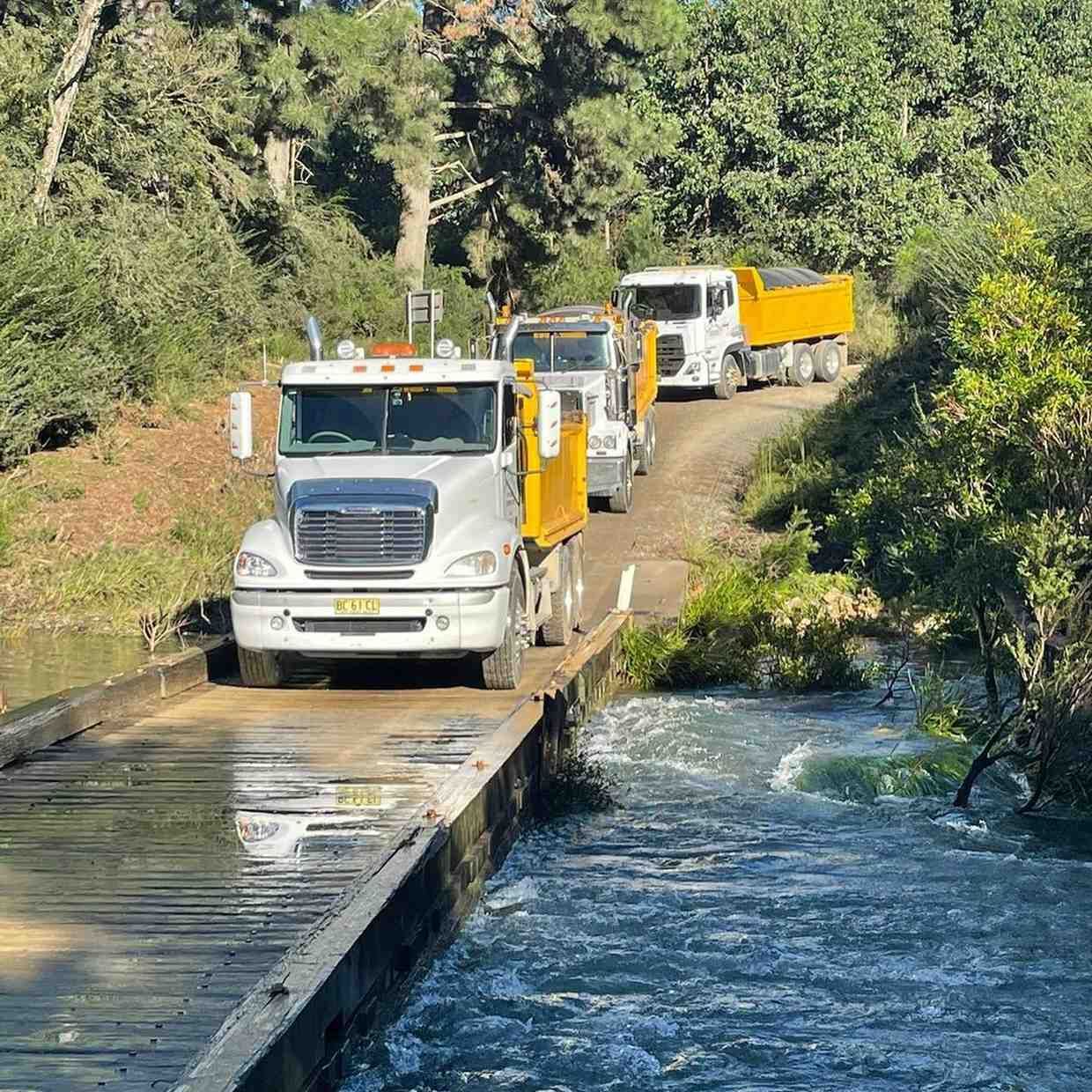 Three Tipper Trucks Crossing a Wooden Bridge — B & D Bunt Earthmoving Contractors in North Boambee Valley, NSW