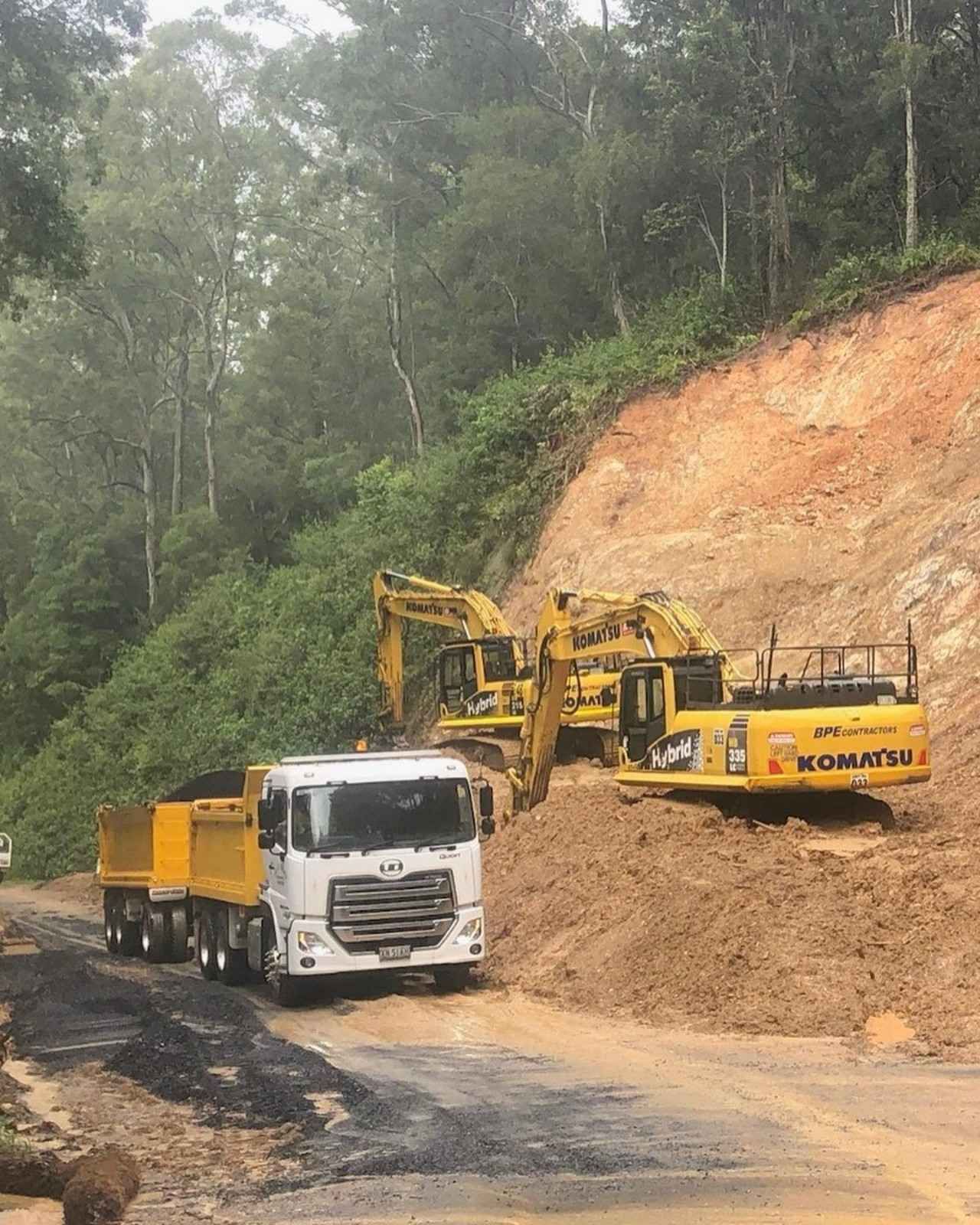 Yellow Excavators Load a Dump Truck on a Muddy Road — B & D Bunt Earthmoving Contractors in North Boambee Valley, NSW