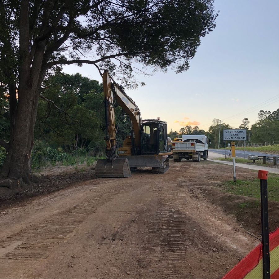 A Excavator on a Dirt Road Next to Trees — B & D Bunt Earthmoving Contractors in Nambucca Heads, NSW