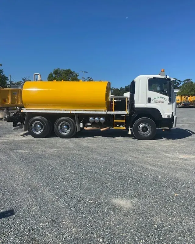 Yellow water tanker truck parked on gravel under a blue sky — B & D Bunt Earthmoving Contractors in North Boambee Valley, NSW