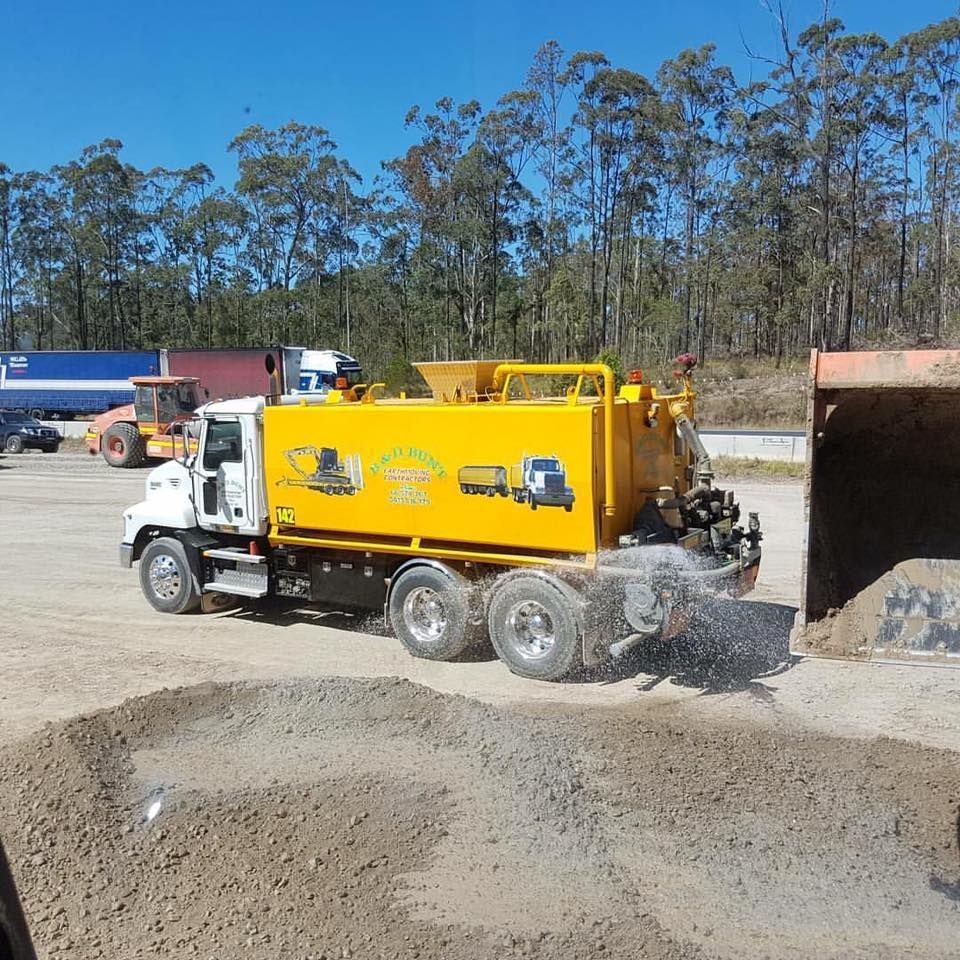 A Yellow Water Truck Spraying — B & D Bunt Earthmoving Contractors in Nambucca Heads, NSW