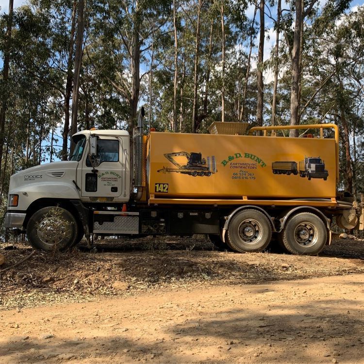 A White and Yellow Truck in a Wooded Area — B & D Bunt Earthmoving Contractors in Coffs Harbour, NSW