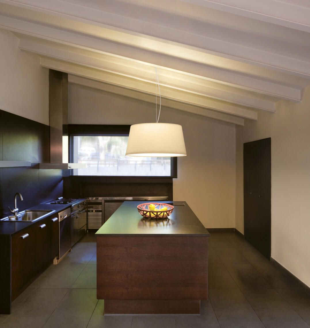 Una cocina moderna con una isla de madera oscura con frutero, armarios oscuros y vigas de techo blancas a la vista.