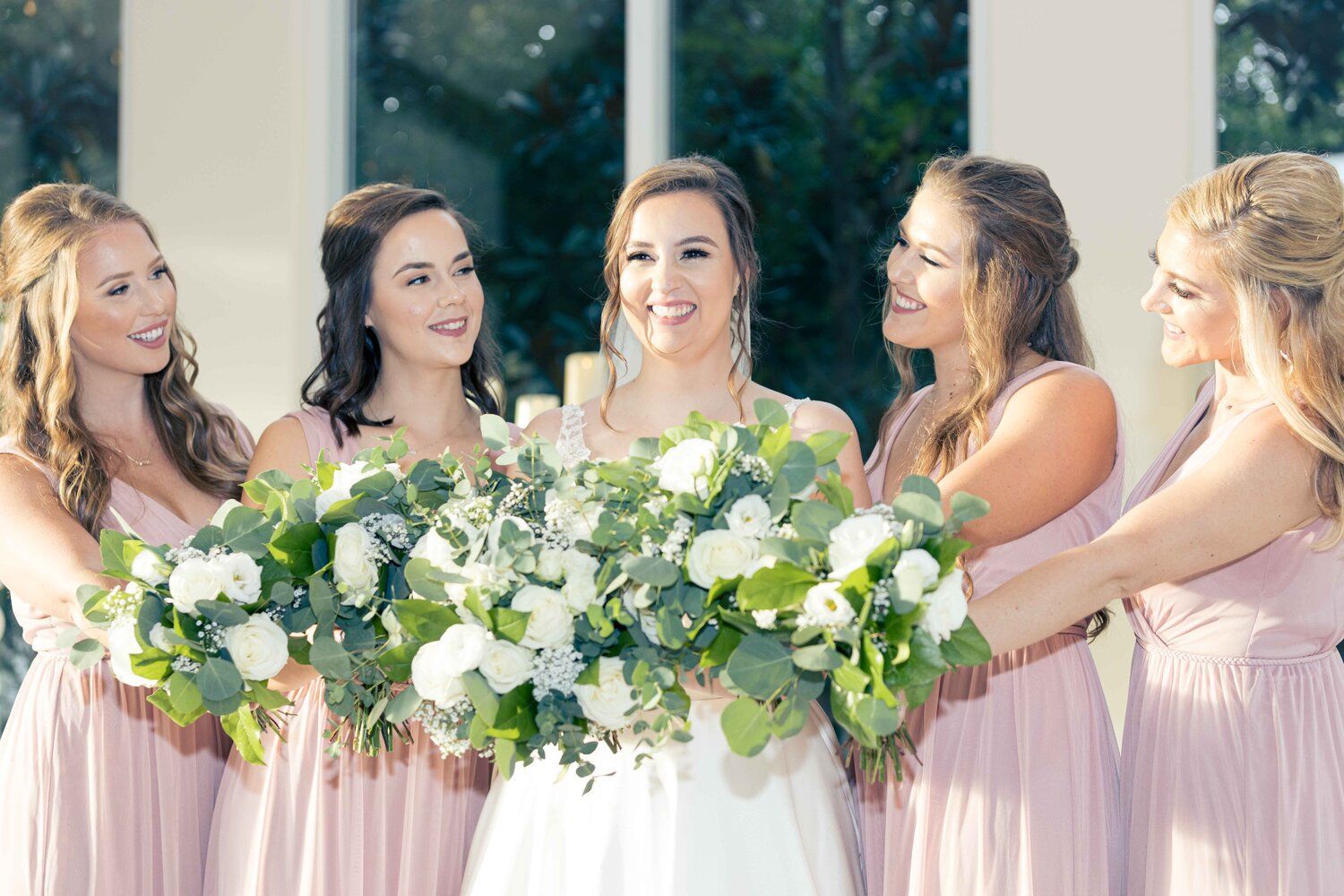 A bride and her bridesmaids are holding a bouquet of flowers.