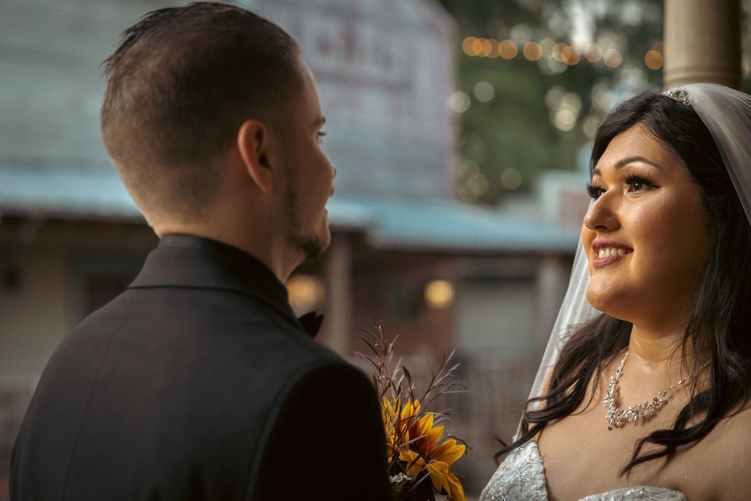 A bride and groom are looking at each other in front of a building.