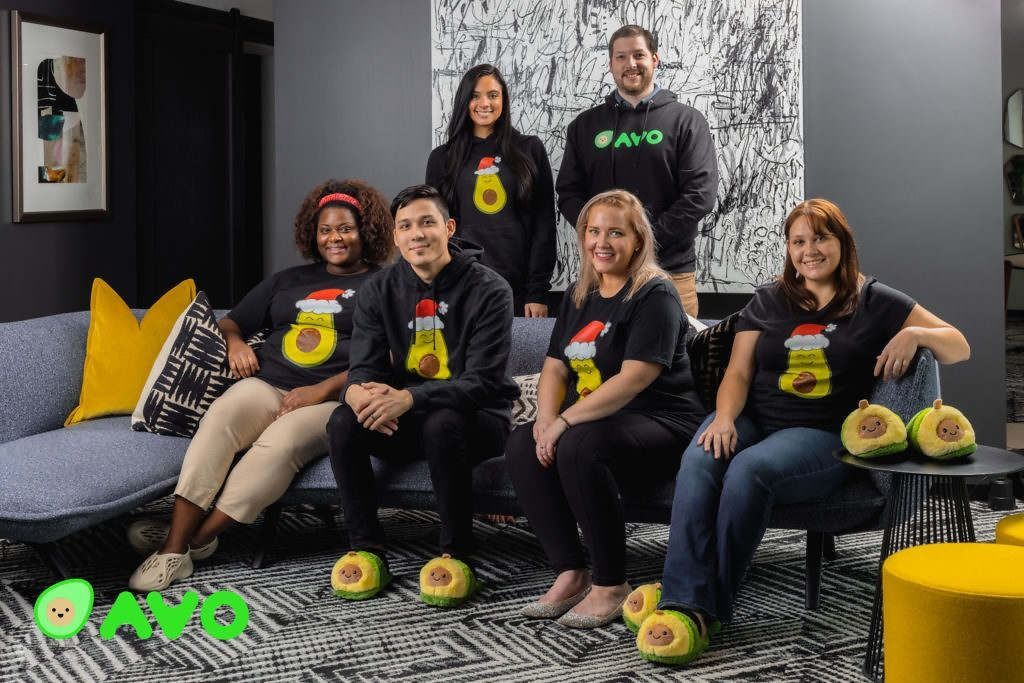 A group of people are sitting on a couch wearing avocado slippers.