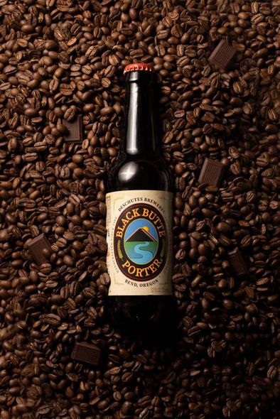 A bottle of beer is sitting on top of a pile of coffee beans.