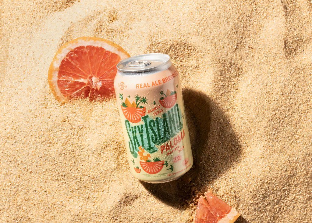A can of sky island beer is sitting on top of a sandy beach.