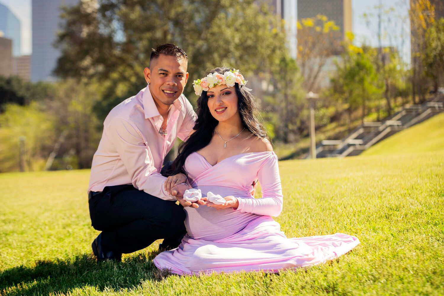 A man is kneeling next to a pregnant woman in a pink dress.