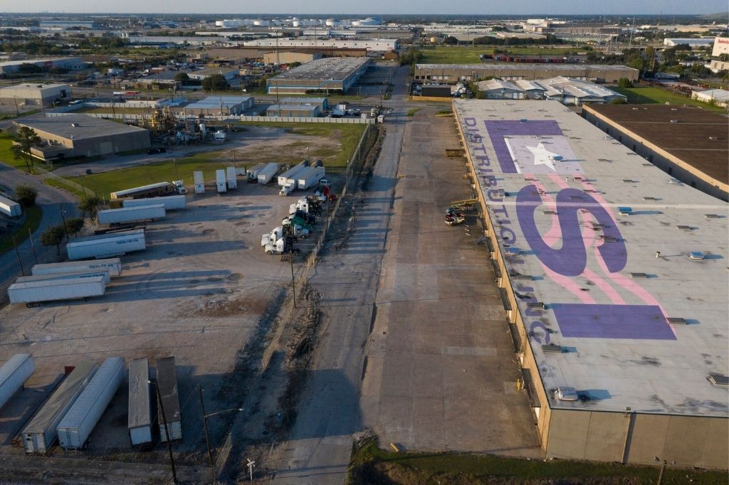 An aerial view of a large building with a large purple sign on the roof.