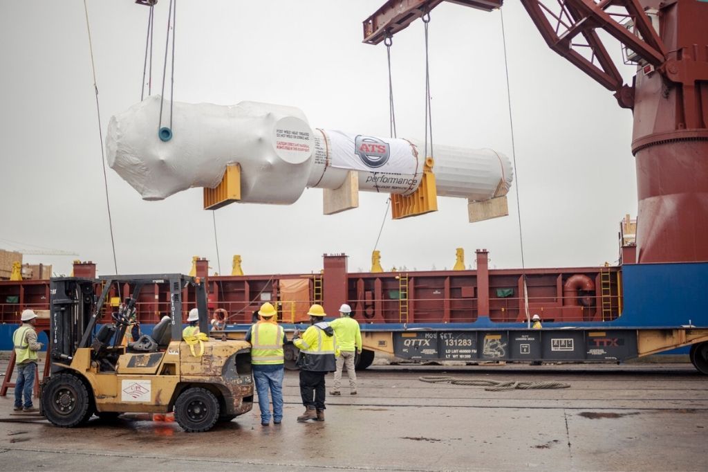 A forklift is lifting a large object from a ship.