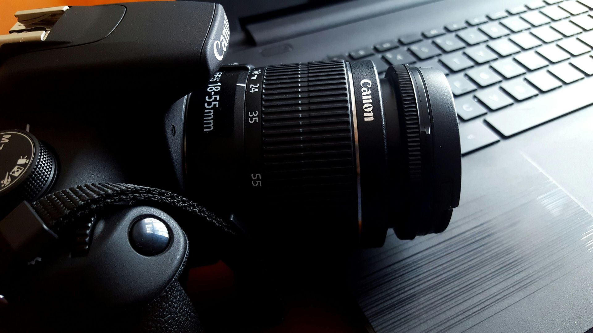 A canon camera is sitting on top of a laptop