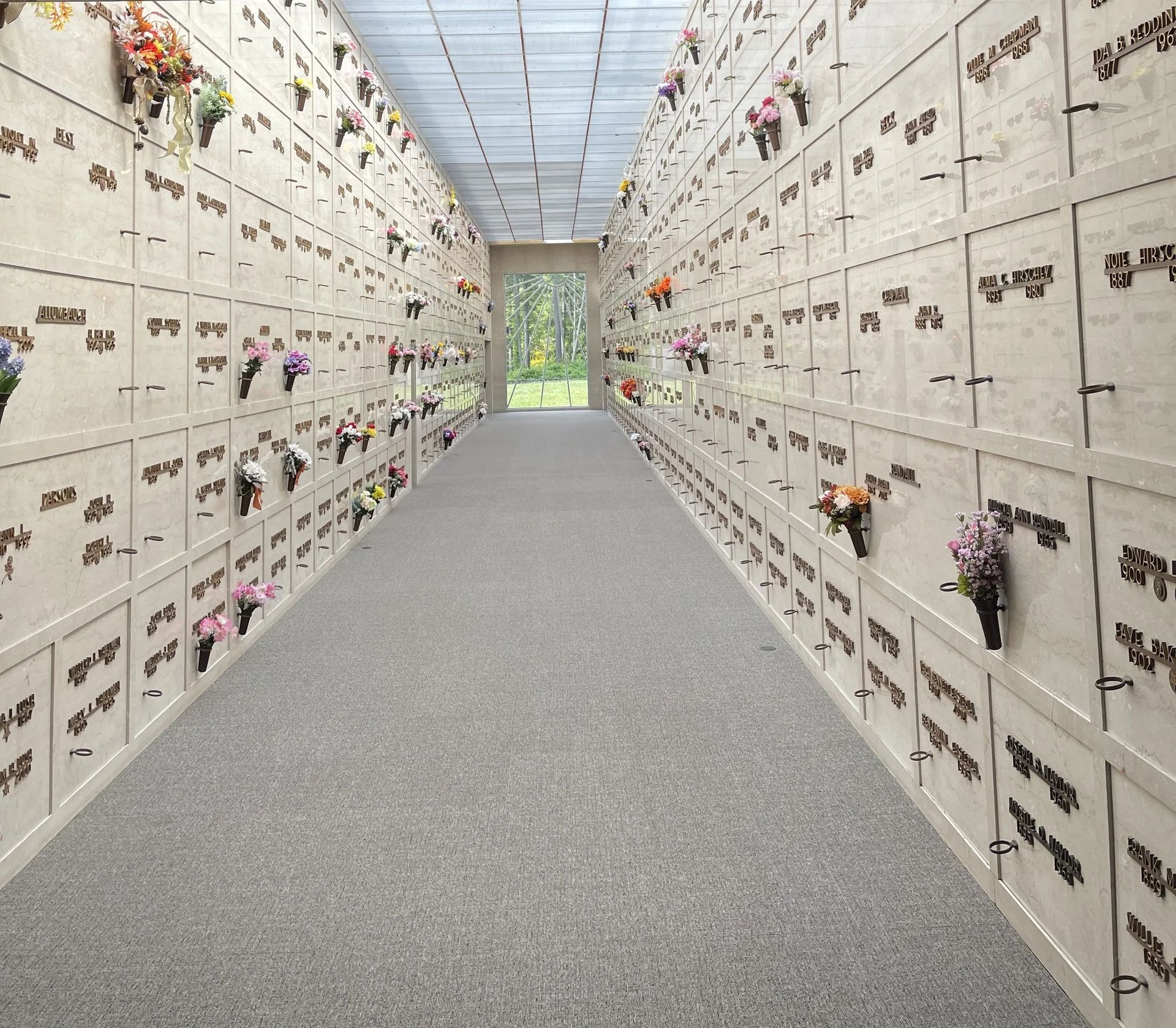 Indoor columbarium with rows of niches, flowers, and a doorway to the outside.