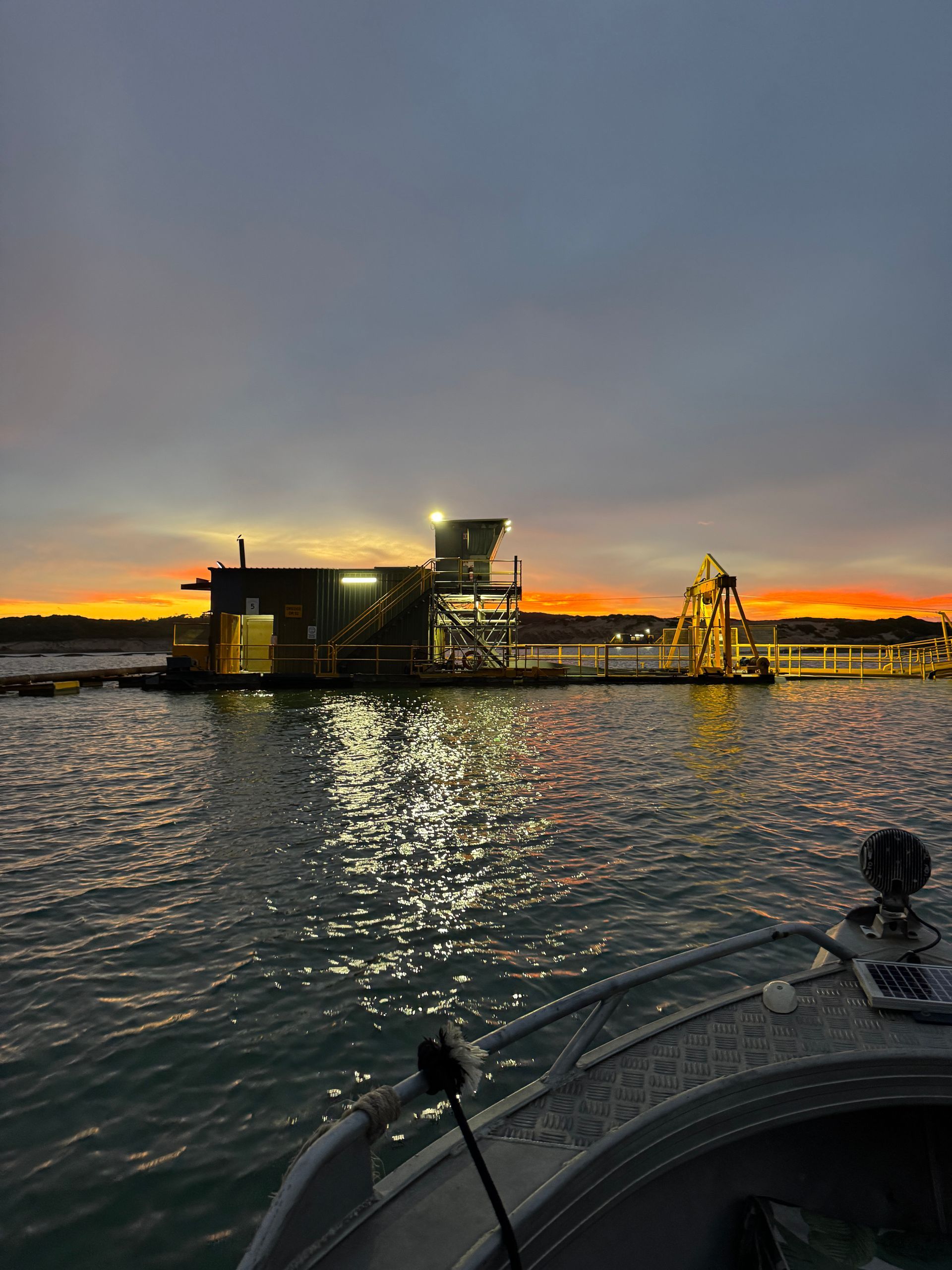 A boat is floating on top of a body of water at sunset.