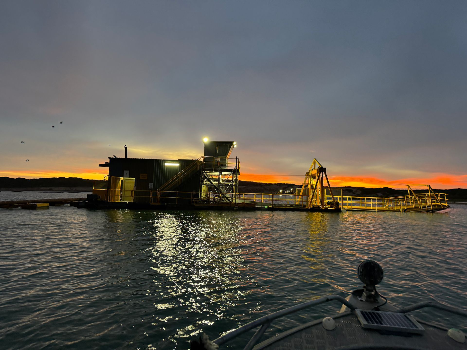 A boat is floating on top of a body of water at sunset.