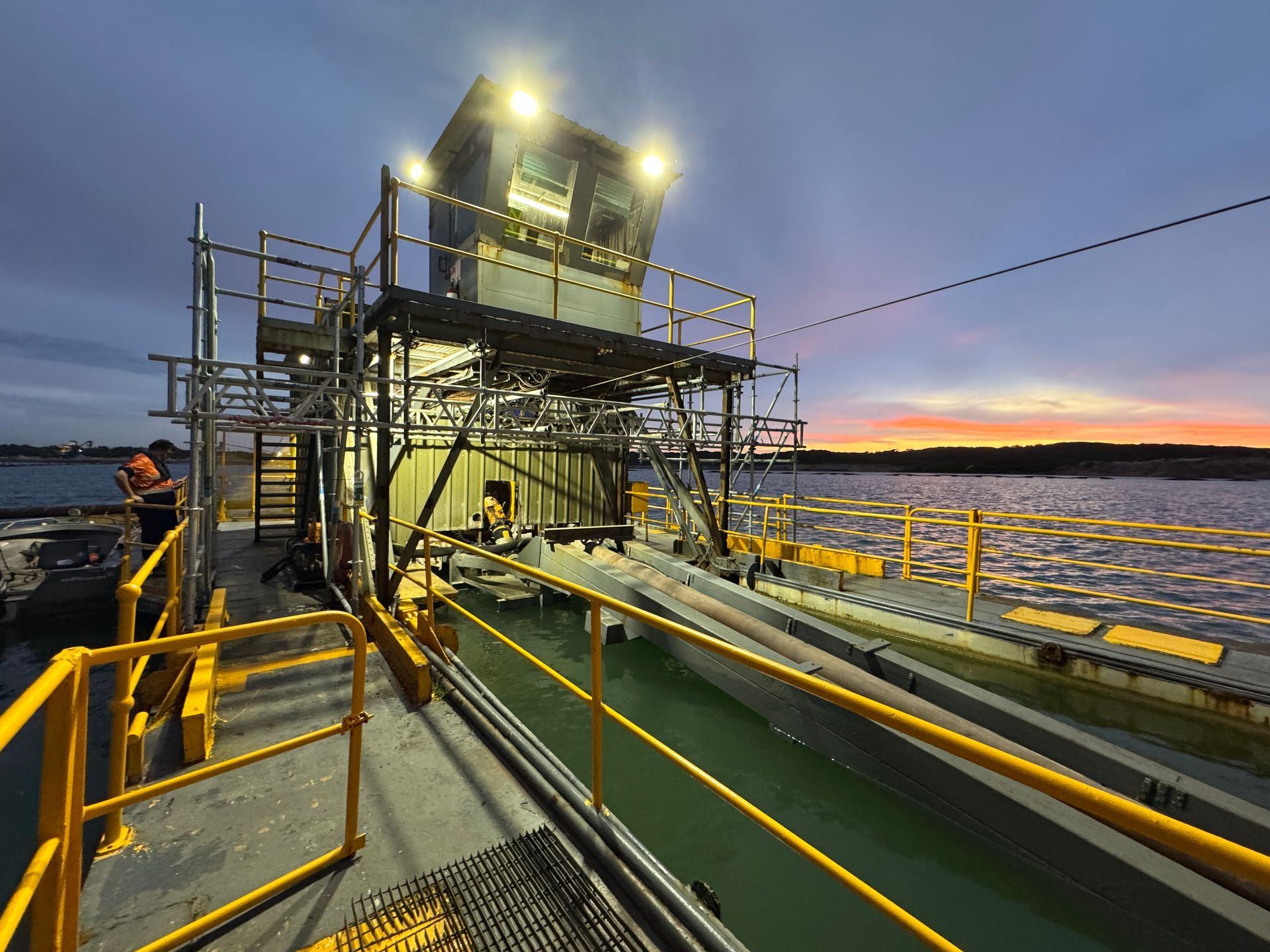 A boat is docked in the water with a sunset in the background.