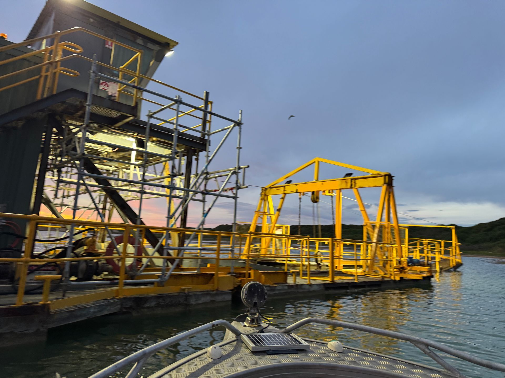 A boat is in the water near a yellow structure