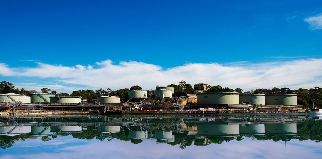 A row of tanks are sitting next to a body of water.