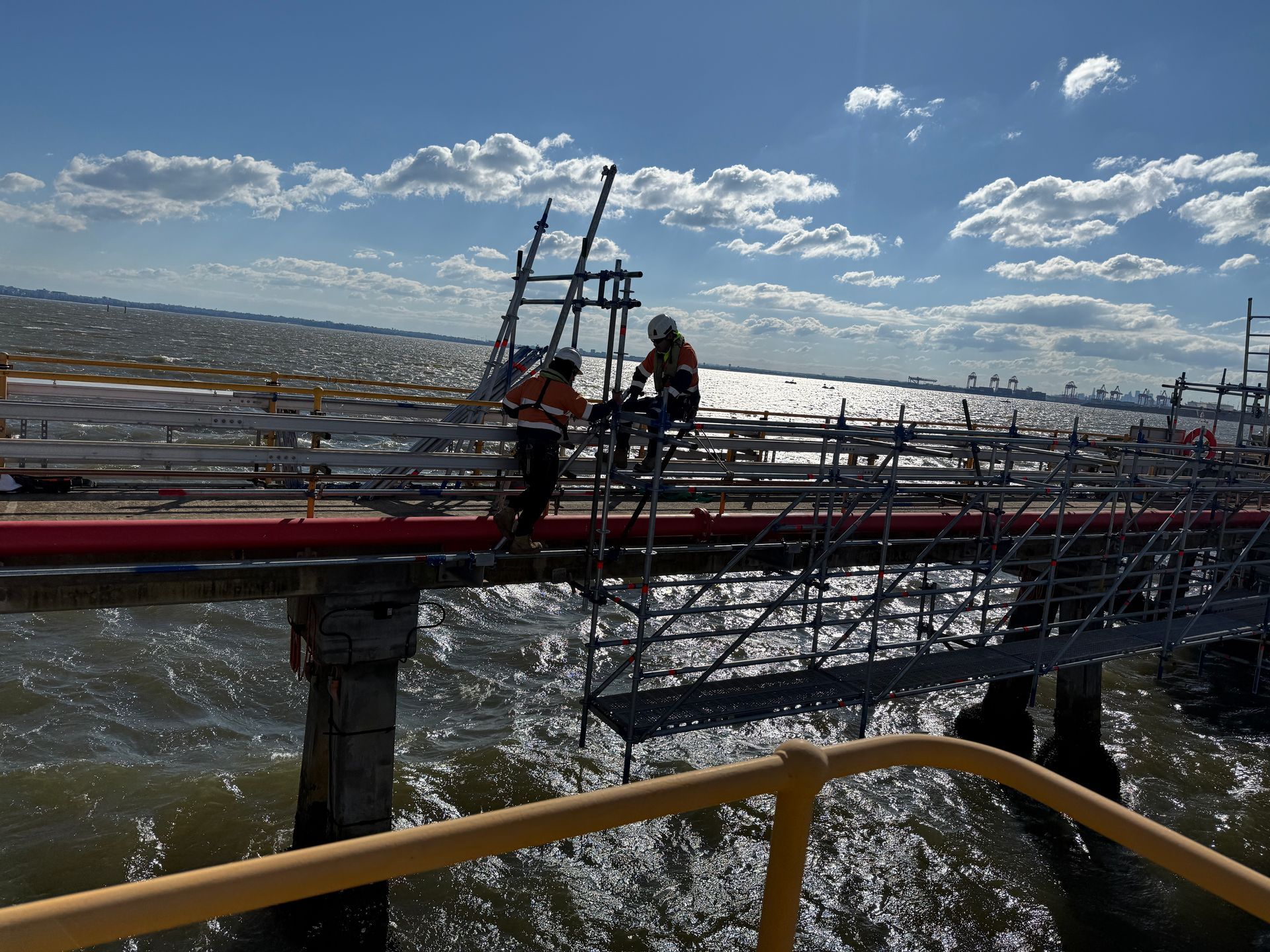 Two men are working on a bridge over a body of water.