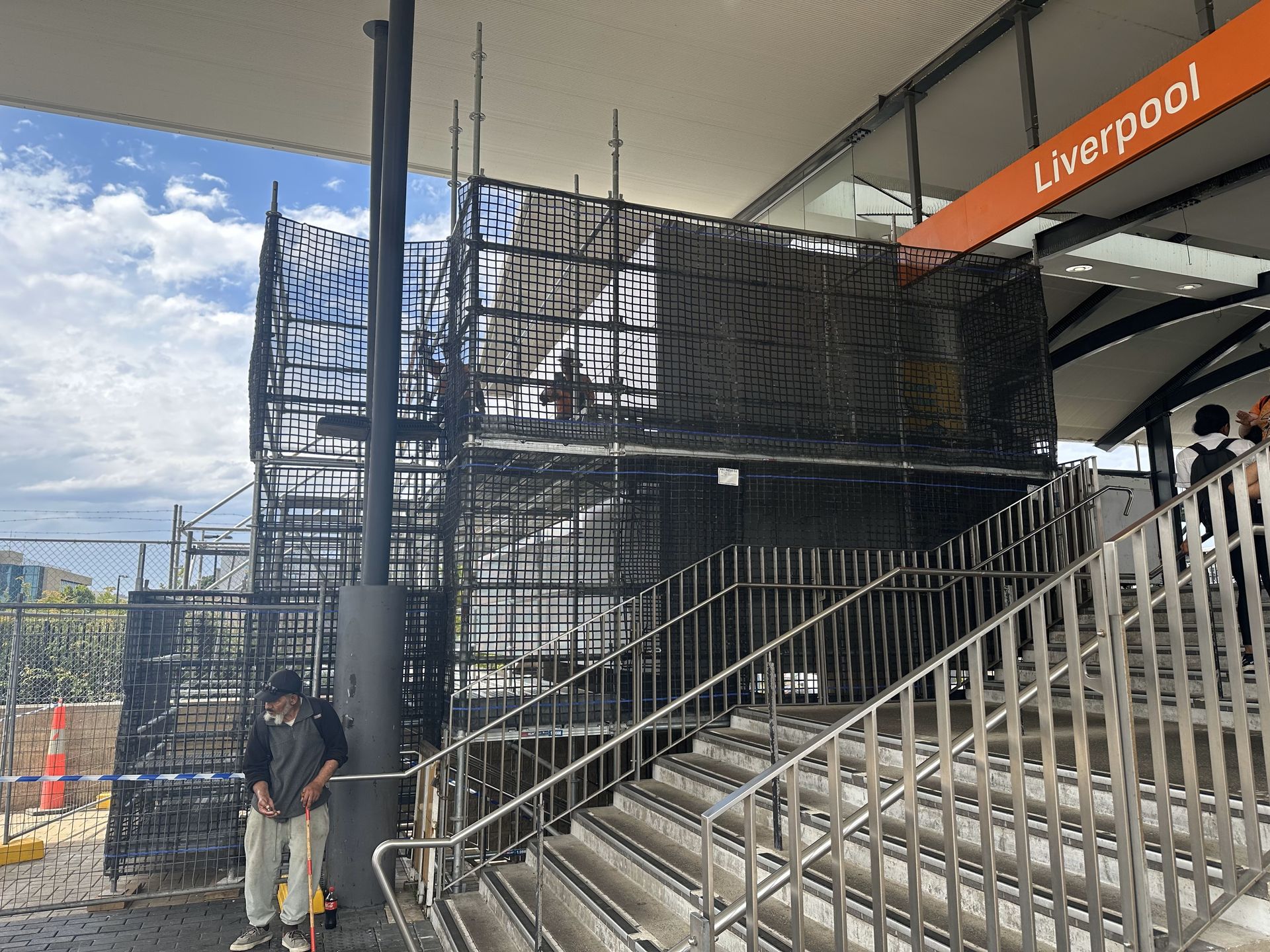 A man is standing on a scaffolding in front of a building.