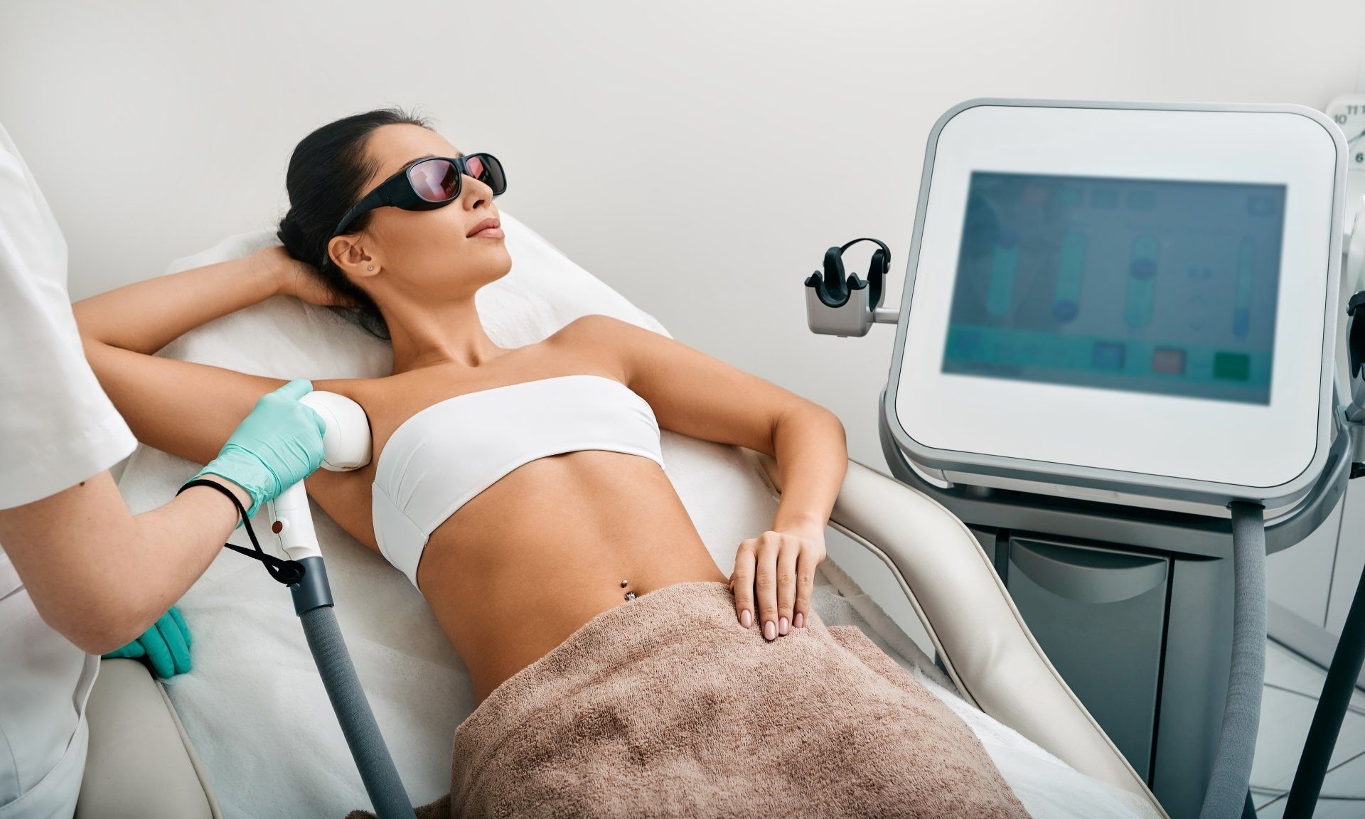 A woman is getting a laser hair removal treatment on her armpits.
